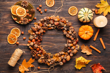 Beautiful acorn wreath, pumpkins, hazelnuts and leaves on dark wooden background