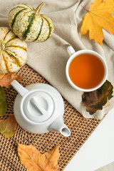 Tea pot, cup of hot beverage and autumn leaves on table