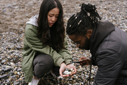 Young Couple Collects Pebbles on the Beach