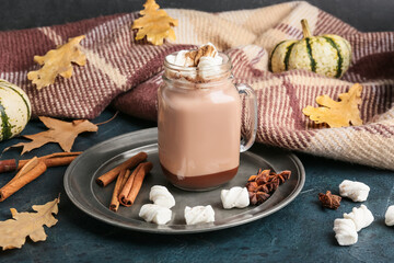 Mason jar of tasty coffee with cinnamon and marshmallows on black background
