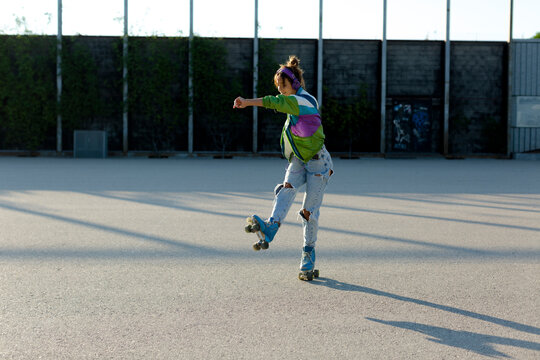 Roller-skater girl doing pirouettes in sunlight outdoor