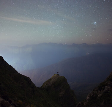 Wanderer on the rock under night sky