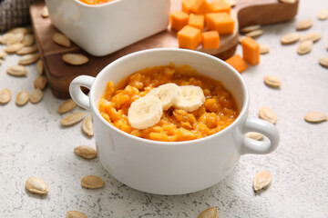 Bowl of tasty oatmeal with pumpkin and banana on white background