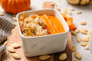 Bowl of tasty oatmeal with pumpkin on white background