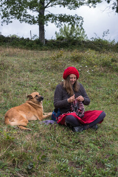 woman knits and dog is happy