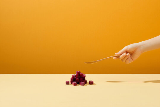 Beetroot cube slice with hand hoding spoon