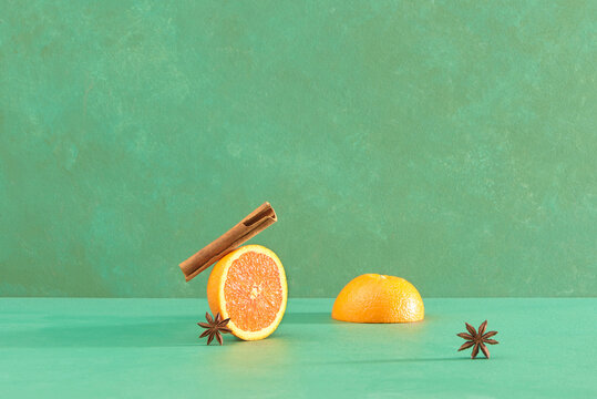 Orange fruit, cinnamon sticks and anise stars on green table