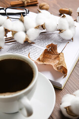 Cup of coffee, branch of cotton flowers, opened book and autumn leaf on wooden table