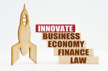 On the white surface there is a wooden rocket and planks, on the red plaque the inscription - INNOVATE