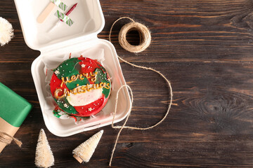 Fototapeta na wymiar Plastic lunch box with tasty bento cake and Christmas decor on wooden background