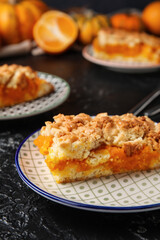 Plates with pieces of tasty pumpkin pie on black background