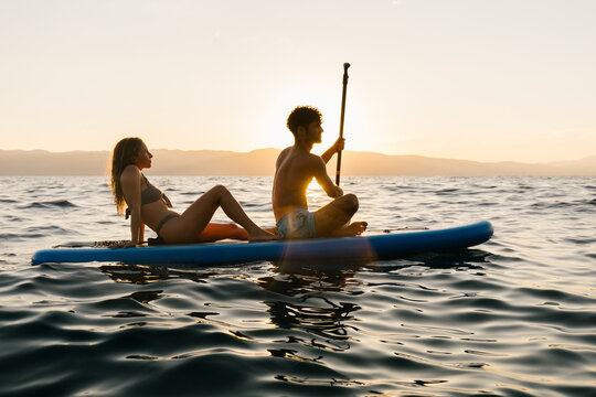 Couple on a sup board with a sunset in background