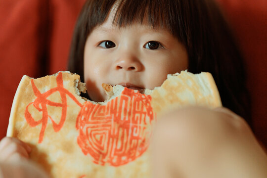 Cute little girl eats a big moon cake.