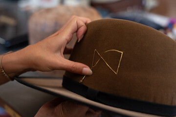 Hands showing a golden thread detail on the hat
