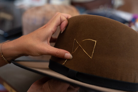 Hands showing a golden thread detail on the hat