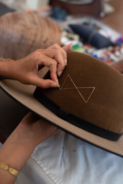 Hands showing a golden thread detail on the hat
