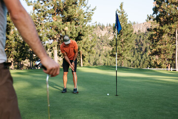 Golfer putting ball on green