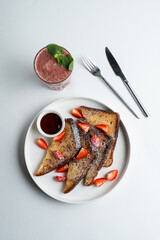 Golden roasted sweet brioche with caramel syrup, strawberry and powdered sugar, top view on white background, gourmet french dessert