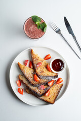 Golden roasted sweet brioche with caramel syrup, strawberry and powdered sugar, top view on white background, gourmet french dessert