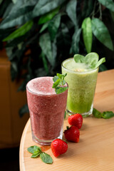 Different smoothies in misted cold glasses, standing on wooden round table, top view