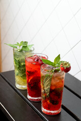 Different mojitos standing in a row on a black wooden bar counter, trendy bar photo