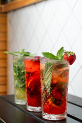 Different mojitos standing in a row on a black wooden bar counter, trendy bar photo