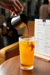 Pouring a shot of espresso into orange juice, close up