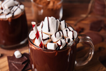 Glass cups of tasty hot chocolate on wooden background, closeup