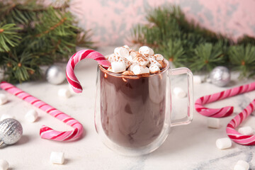 Glass cup of tasty hot chocolate with marshmallows and candy canes on white marble background