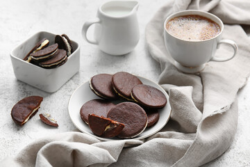 Plate with tasty chocolate cookies, milk and cup of coffee on light background