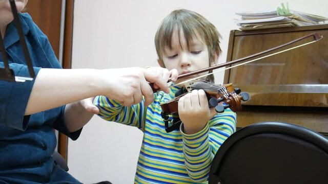 A music teacher teaches a boy the basics of playing a violin