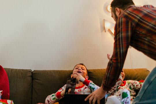 Laughing boys opening Christmas presents with dad