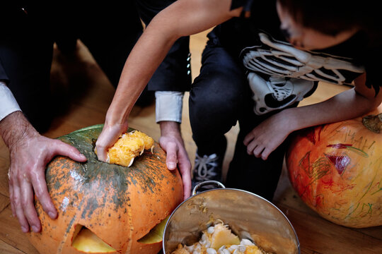 Incognito male person pulling seeds from carved pumpkin