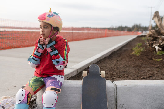 Skateboarding girl fastens helmet