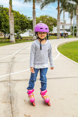 Little girl is skating with her roller skates on the rink