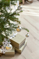 Beautiful Christmas tree decorated with snowflakes and balls with gift boxes in room, closeup