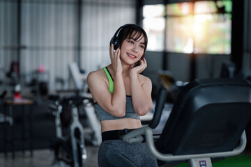 Portrait of young Asian woman with smartphone listening to music in gym.
