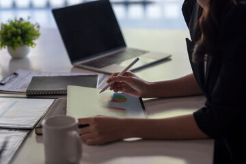 Businesswoman using tablet analyzing chart and graph investment information in office.