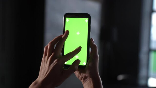 Close film of green screen on iphone. Girl holds in hands mobile phone device with moving interactive motion tracking points. Touching, tapping smartphone surface with fingers, sliding and swiping.