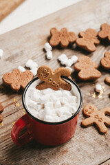 Fototapeta na wymiar ginger man in a cup of cocoa with a big red bow on a wooden background, top view. Various Christmas sweets with a cup of cocoa on the table. Christmas flatlay