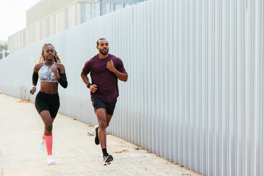 Sportswoman with trainer running on street