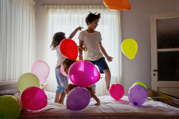 Three excited boys jumping on bed