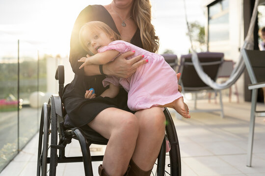 Unrecognizable mom in wheelchair with her daughter