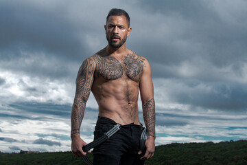 Sexy man with naked torso. Brutal angry gang man lifestyle, serious handsome guy. Strong muscular male body, muscles guy. Tattooed and elegant hipster.