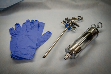 an instrument for performing a prostate resection lies next to blue medical gloves and a glass bulb...