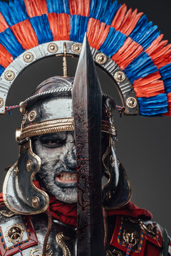 Dead roman soldier with bloody sword against gray background