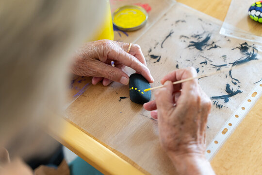 Close-up of woman painting stones with a brush