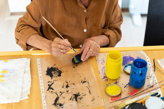 Close-up of woman painting stones with a brush