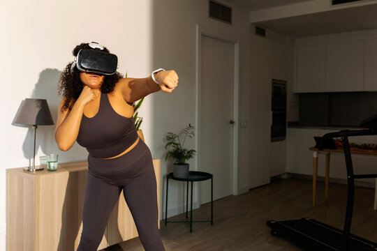 Woman boxing with virtual reality glasses indoor - Powered by Adobe