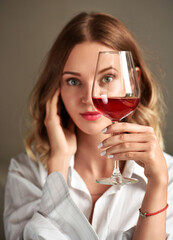 Glass of red wine in the hand of an attractive young girl